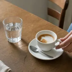 Una mano afferra una tazza di cappuccino su un tavolo di legno. Ti chiedi quante calorie ha un cappuccino?
