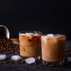 Due bicchieri di crema di caffè senza panna, con chicchi di caffè e cubetti di ghiaccio sparsi.