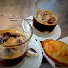 Due caffè salentino con ghiaccio e una pastarella su un tavolino.