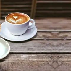 Due tazze di caffè con schiuma decorata, una in bicchiere e una in tazza bianca. Illustrano la differenza tra latte macchiato e caffelatte.