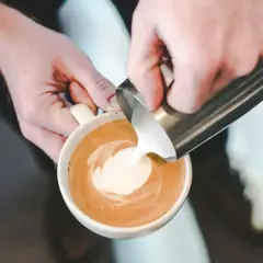 Barista crea un disegno con latte schiumato su un caffè.