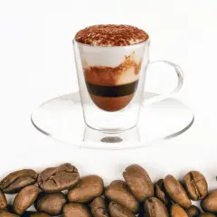 Un bicerin coffee a strati in una tazza di vetro, con cacao in polvere in cima e chicchi di caffè tostati sul fondo.