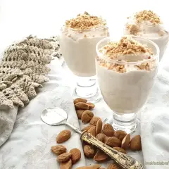 Delizioso espressino freddo pugliese in bicchieri, guarnito con mandorle tritate. Accanto, mandorle intere e un cucchiaino.