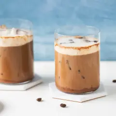 Due bicchieri di caffè freddo con schiuma e cacao, perfetti per una ricetta estiva.