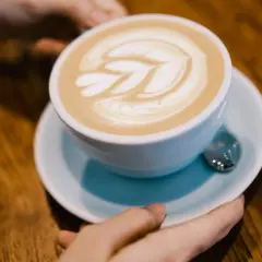 Un flat white con schiuma artistica, pronto per essere gustato su un tavolo di legno.