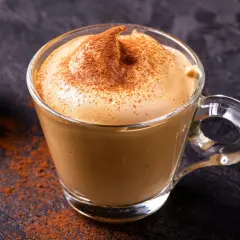 Una tazza di crema di caffè fatta in casa, spolverata di cacao, su uno sfondo scuro.