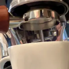 Manuale per capire come mettere le cialde nel portafiltro, con una tazzina bianca pronta a ricevere l'espresso.