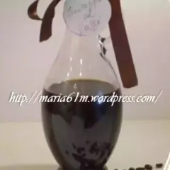 Caraffa di sciroppo al caffè fatto in casa, con etichetta scritta a mano e chicchi di caffè sparsi.