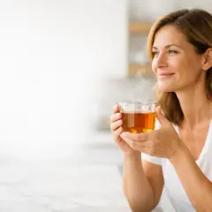 Donna sorride mentre beve una tazza di tè nero caldo, un alleato per chi vuole che il tè nero fa dimagrire.
