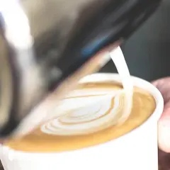 Un barista crea un cuore di latte art su un caffè. Il latte si monta caldo o freddo, creando una schiuma perfetta per il cappuccino.
