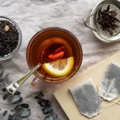 Tazza di tè Earl Grey con limone, foglie di tè sfuse e bustine. Scopri i benefici del tè Earl Grey per il tuo benessere.