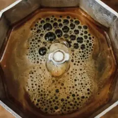 Caffè bollente nella moka, con bollicine che ricordano i sintomi dell'astinenza da caffeina.