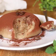 Delizioso budino al caffè, cosparso di cacao e chicchi di caffè, con una fogliolina di menta fresca.