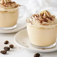 Due cappuccini con panna e cacao, un'idea per come fare il cuore nel cappuccino. Chicchi di caffè sparsi.