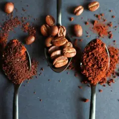 Tre cucchiai: uno con chicchi di caffè, gli altri due con la dose caffè per una tazzina, pronti per un'ottima colazione.