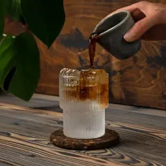 Versando caffè in un bicchiere con ghiaccio e acqua frizzante. Un'idea rinfrescante per l'estate.