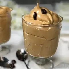 Deliziosa spuma di caffè in bicchieri, guarnita con chicchi di caffè. Perfetta per una pausa golosa.