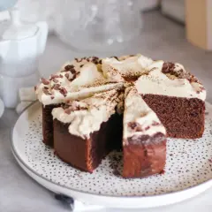 Una fetta di torta caffè e cioccolato, ricoperta di panna e scaglie di cioccolato, pronta per essere gustata con un caffè.