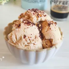 Coppetta di gelato al caffè, guarnita con scaglie di cioccolato e nocciole croccanti. Perfetto per una pausa golosa.
