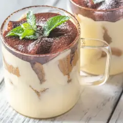 Delizioso monoporzione tiramisù in bicchiere, guarnito con cacao e menta fresca.