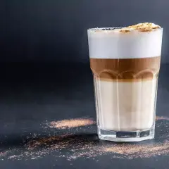 Un bicchiere di latte macchiato con strati distinti di latte, caffè e schiuma. Ecco come si fa, un piacere visivo e gustativo.