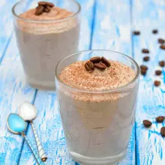 Delizioso sorbetto al caffè ricetta, guarnito con chicchi di caffè e cacao, servito in bicchieri su un tavolo di legno blu.