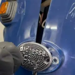 Dettaglio di una macchina del caffè blu, con un'etichetta "didiesse" e un guanto grigio che lavora su di essa.