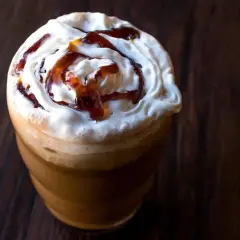 Frappuccino ricetta: un bicchiere di caffè freddo con panna montata e sciroppo caramello, perfetto per una pausa golosa.