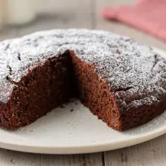 Una deliziosa torta caffè e cioccolato fondente, cosparsa di zucchero a velo, con una fetta mancante.