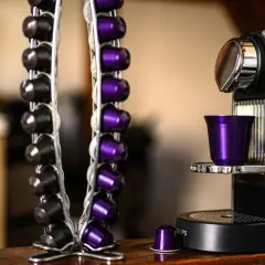 Macchina caffè Caffitaly con spia rossa lampeggiante. Capsule nere e viola in un portacapsule accanto.