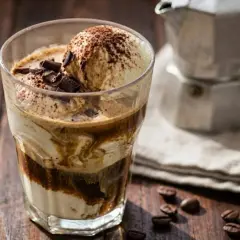 Un delizioso gelato affogato al caffè, guarnito con scaglie di cioccolato e cacao, pronto per essere gustato.