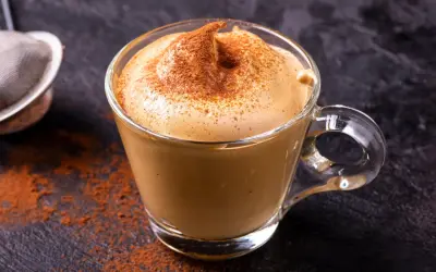 Una tazza di crema di caffè fatta in casa, spolverata di cacao, su uno sfondo scuro.