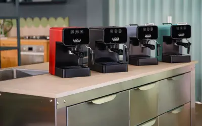 Macchine da caffè Gaggia in vari colori, una rossa, una nera, una grigia e una verde acqua, disposte su un bancone. Speriamo che la macchina caffè Gaggia non esca il caffè, altrimenti la colazione è rovinata!