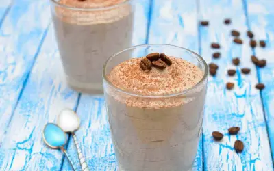 Delizioso sorbetto al caffè ricetta, guarnito con chicchi di caffè e cacao, servito in bicchieri su un tavolo di legno blu.