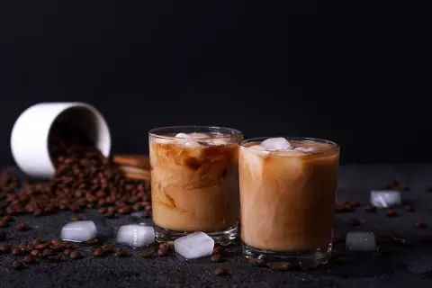 Due bicchieri di crema di caffè senza panna, con chicchi di caffè e cubetti di ghiaccio sparsi.