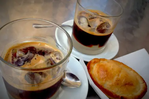 Due caffè salentino con ghiaccio e una pastarella su un tavolino.