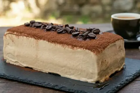 La mattonella della nonna al caffè, ricoperta di cacao e chicchi di caffè, pronta per essere gustata con un espresso.