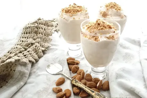 Delizioso espressino freddo pugliese in bicchieri, guarnito con mandorle tritate. Accanto, mandorle intere e un cucchiaino.