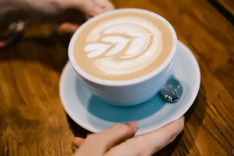 Un flat white con schiuma artistica, pronto per essere gustato su un tavolo di legno.