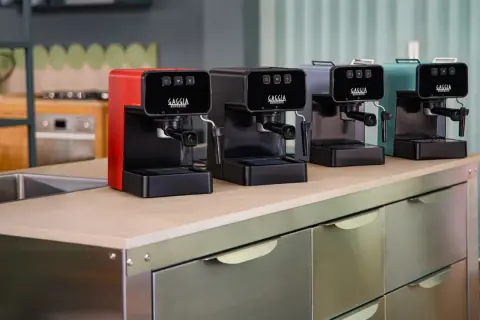 Macchine da caffè Gaggia in vari colori, una rossa, una nera, una grigia e una verde acqua, disposte su un bancone. Speriamo che la macchina caffè Gaggia non esca il caffè, altrimenti la colazione è rovinata!