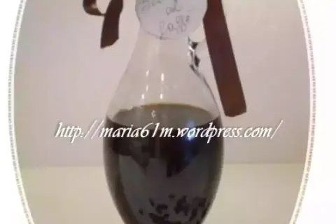 Caraffa di sciroppo al caffè fatto in casa, con etichetta scritta a mano e chicchi di caffè sparsi.