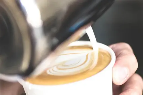 Un barista crea un cuore di latte art su un caffè. Il latte si monta caldo o freddo, creando una schiuma perfetta per il cappuccino.