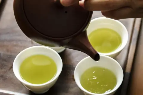 Versando tè verde in tazze. Quante tazze di tè verde bere al giorno? Un rituale rilassante.