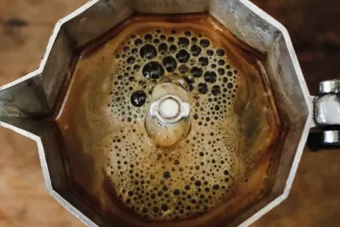 Caffè bollente nella moka, con bollicine che ricordano i sintomi dell'astinenza da caffeina.
