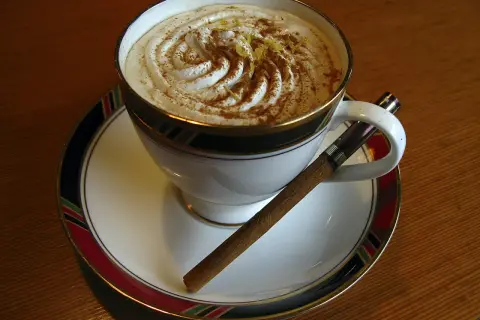 Caffè Pedrocchi ricetta: una tazza di caffè con panna montata, cannella e scorza di limone, accompagnata da un sigaro.