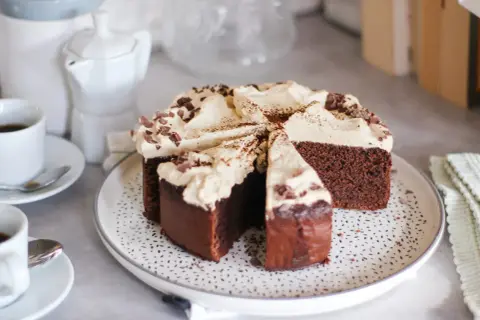 Una fetta di torta caffè e cioccolato, ricoperta di panna e scaglie di cioccolato, pronta per essere gustata con un caffè.