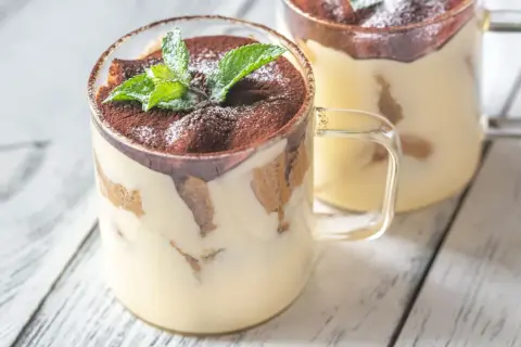 Delizioso monoporzione tiramisù in bicchiere, guarnito con cacao e menta fresca.