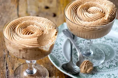 Due coppe di deliziosa mousse di caffè, guarnite a spirale, su un piatto decorato.