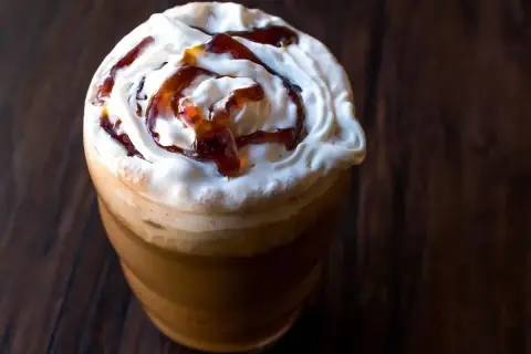 Frappuccino ricetta: un bicchiere di caffè freddo con panna montata e sciroppo caramello, perfetto per una pausa golosa.