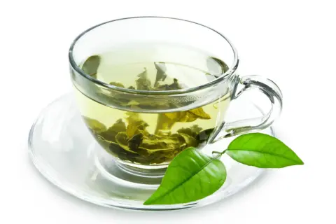Tazza di tè verde con foglie infuse, un invito a scoprire i suoi benefici.